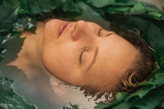 Attractive blonde woman bathes in medicinal herbs.
