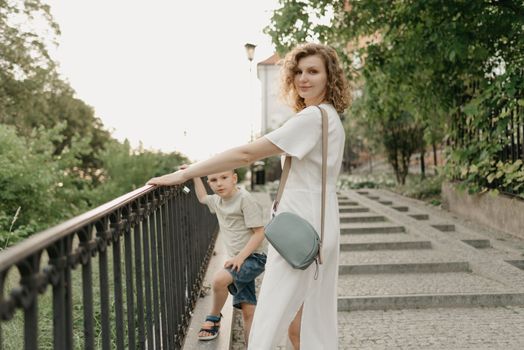 Mother and son are staring near the parapet on the green cobbled street of an old European town. Happy family in the evening. Tourists at sunset.