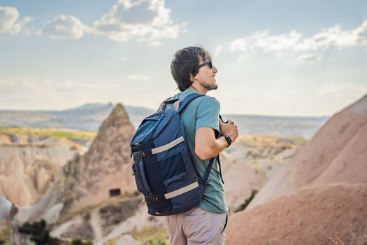 Young man exploring valley with rock formations and fairy caves near Goreme in Cappadocia Turkey.