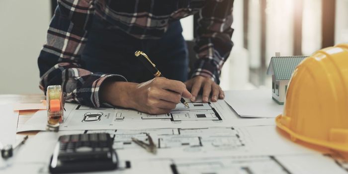 Concept architects, engineer holding pen pointing equipment architects On the desk with a blueprint in the office