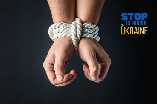 tightly tied hands with a white rope on dark background, violence and kidnapping. with words stop genocide in ukraine. concept needs help and support, truth will win