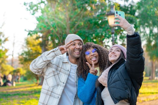 Diverse cultures students taking selfie with mobile phone outdoors at campus. University college people having fun together. High quality photo