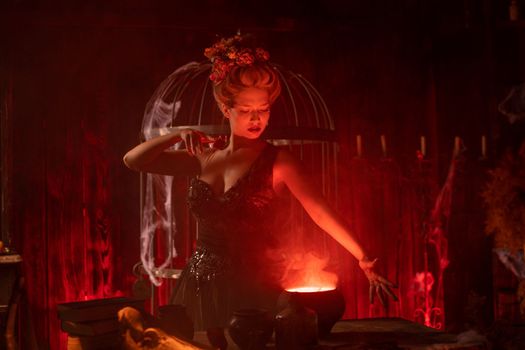 Witch with cauldron. Beautiful young woman conjuring, making witchcraft. Standing spooky dungeon dark room. Enchantress prepare love potion use magic spell