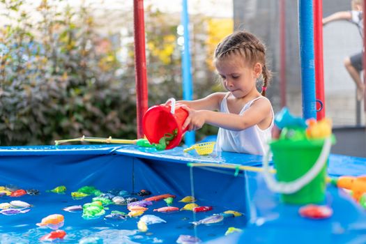 Child Fisher Catching Plastic Toy Fish On Pool Amusement Park Summer Day Little Girl Have Fun On Fishing Carnival Festival Entertainment For Children