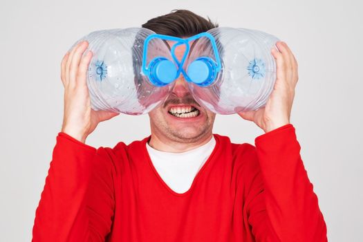 Recycle waste management concept. Caucasian man hiding behind an empty water bottle.