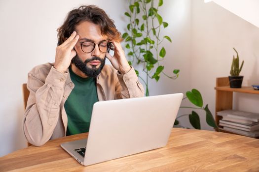 Stressed tired businessman suffering from headache working from home - Worried male entrepreneur thinking about problems and project deadline feeling burnout distress and exhausted. High quality photo