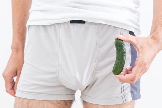 a man in underwear holds a cucumber.