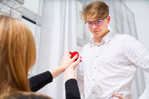 Embarrassing moment. Romantic concept. Young woman holding box with engagement ring, making marriage proposal to her boyfriend indoors, women psychology.