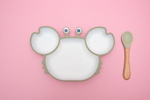 Cute children's plate in crab shape on pink background. Serving baby. Concept for kids menu, nutrition and feeding. Funny bowl.