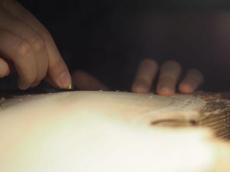artisan working on raw wood violin plate with finger plane on the bench