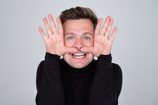 Funny young Caucasian man grimacing, having stupid and ridiculous facial expression.