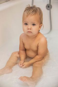 blonde baby bathes in the bathroom.