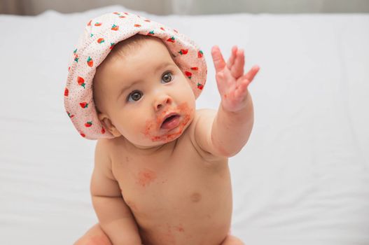 cute stained by strawberry baby reaching hand for her parents.