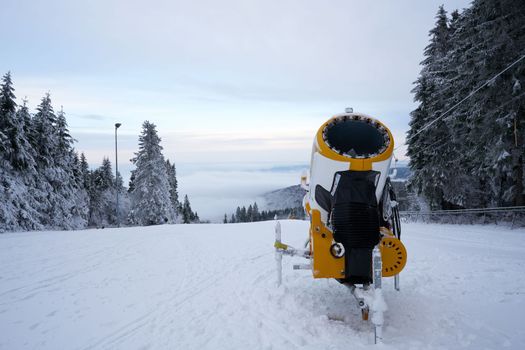 Yellow artificial snow cannon on Wasserkuppe ski resort in Rhoen Hesse Germany, on snowy mountain after fresh snow fall in 2022 december. High quality photo