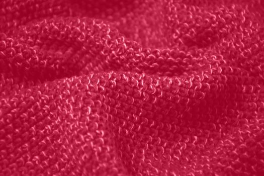Viva Magenta toned colour monochrome texture knitted fabric. Dark pink knitted Jersey as textile background. Monochrome color background. Trendy color 2023.