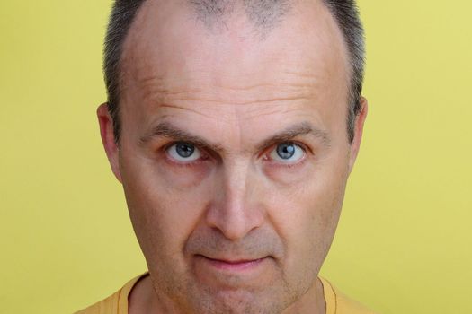 Close-up portrait of a handsome man 45-55 years old on a yellow background.