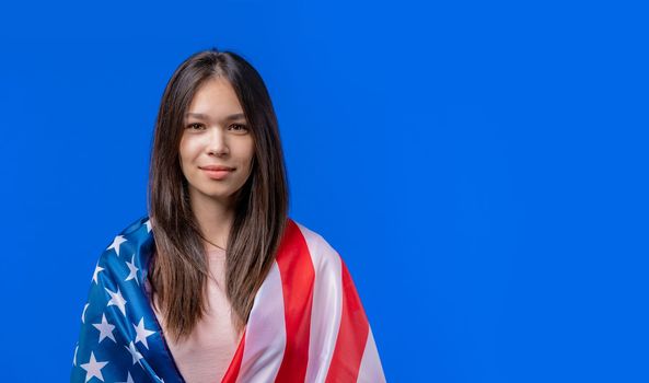Smiling teenager girl with national USA flag on blue background. American patriot, 4th of July - Independence day celebration, election, America, labor. US banner. High quality photo