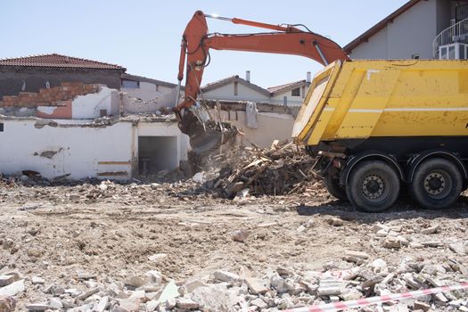 excavator loading debris of a destroyed building in truck.