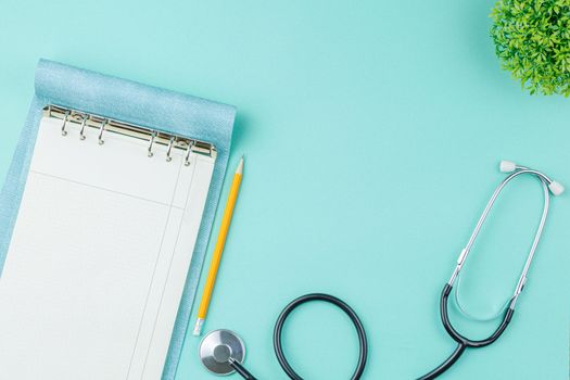 Stethoscope and open notepad in doctor office on green desk background top view. Nurse desktop concept.