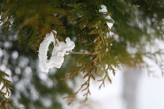 Christmas toy horse hanging on a green branches in the snow in winter. Christmas tree, toy horse, gift. New Year decor.