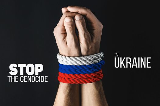 male hands tied with red blue white rope on dark background, violence and kidnapping. with words stop genocide in ukraine. concept needs help and support, truth will win