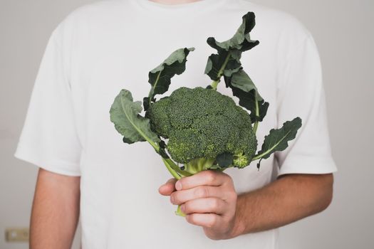 Caucasian man holding fresh broccoli. Healthy food concept.