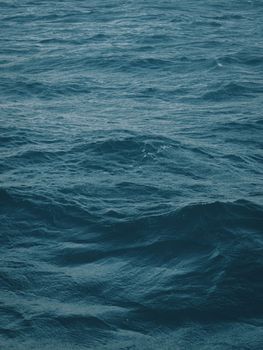 Dark blue-green color of water surface with waves in middle of endless deep sea. Endless wavy expanse of blue sea water. Dark blue waves in deep ocean. Raging aquamarine waves on surface of the water