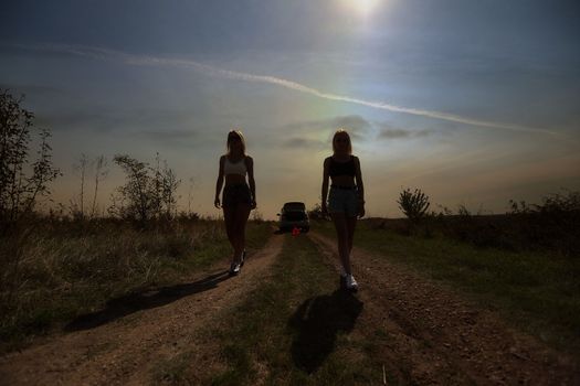 an accident on the road, a car broke down, two beautiful girl models are waiting. A problem with the car. Friends waiting for service. In the countryside . High quality photo