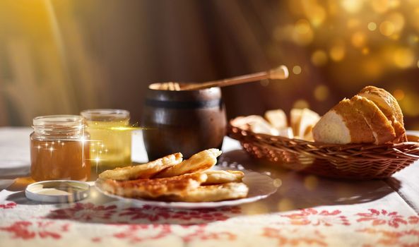 a jar of sweet honey on a table from a garden with apples in a bowl drips from a brush from a spoon a glass jar with cheese and roses and fresh bread with bright light beautiful decoration creative photo in a bucket on a wooden table in a garden with flowers for breakfast delicious food. High quality photo