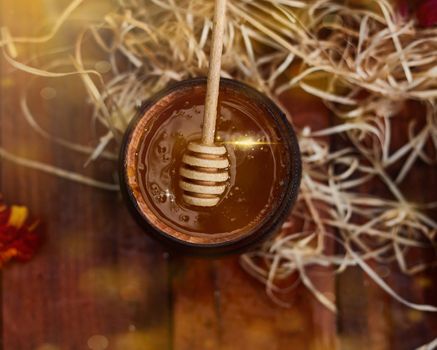 a jar of sweet honey in a bucket on a wooden table in the garden with flowers for breakfast delicious food. High quality photo