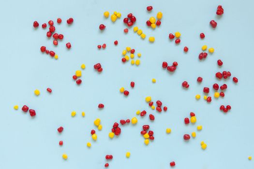 Red and yellow colored candy nerds sprinkled on a blue background