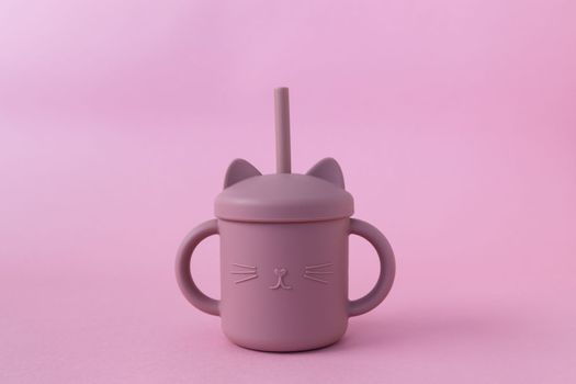 Modern pastel color silicone sippy cups with straws on pink background. Cute baby tableware, first feeding, serving concept. Funny cup
