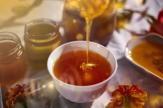 a jar of sweet honey on a table from a garden with apples in a bowl drips from a brush from a spoon a glass jar with cheese and roses and fresh bread with bright light beautiful decoration creative photo in a bucket on a wooden table in a garden with flowers for breakfast delicious food. High quality photo