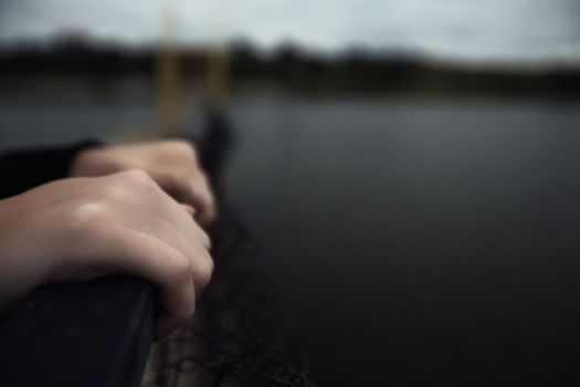 bullying teen girl aloofness young detachment a lonely helpless woman thinks about life and does not want to live looks at a gloomy photo into the distance and a renunciate thinks alone with herself and is bored upset on a pier by the water sits on a pier in the evening. High quality photo