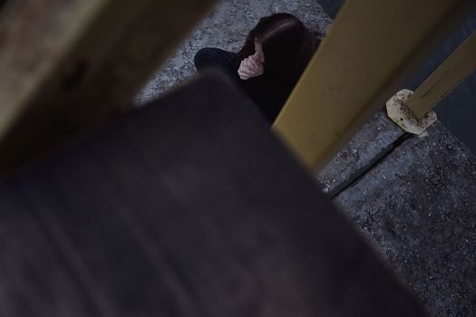 bullying teen girl aloofness young detachment a lonely helpless woman thinks she sits in black clothes about life and does not want to live looks at a gloomy photo into the distance and a renunciate thinks alone with herself and is bored upset on a pier by the water sits on a pier in the evening. High quality photo