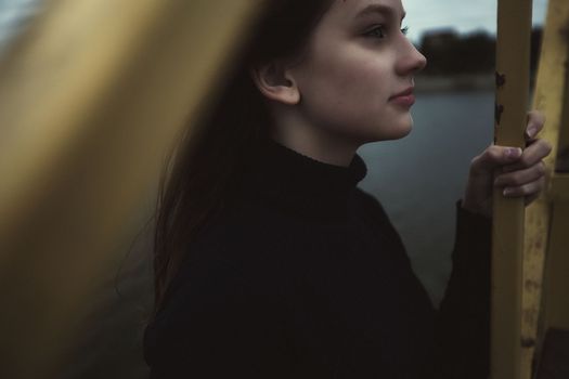 girl bullying loneliness by the water lake teenager alone in solitude trying isolation cope with anger and find strength in the evening gloomy photo abandonment thinking about fate is not easy and hard mooring at the pier. High quality photo