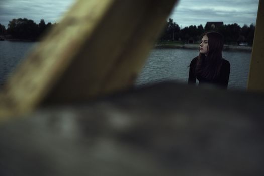 girl bullying loneliness by the water lake teenager alone in solitude trying isolation cope with anger and find strength in the evening gloomy photo abandonment thinking about fate is not easy and hard mooring at the pier. High quality photo