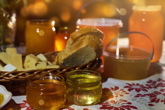 a jar of sweet honey on a table from a garden with apples in a bowl drips from a brush from a spoon a glass jar with cheese and roses and fresh bread with bright light beautiful decoration creative photo in a bucket on a wooden table in a garden with flowers for breakfast delicious food. High quality photo