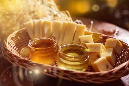 a jar of sweet honey with cheese and roses and fresh bread with bright light beautiful decoration creative photo in a bucket on a wooden table in the garden with flowers for breakfast delicious food. High quality photo