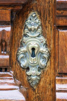 An antique metal lock on a varnished wooden door close up