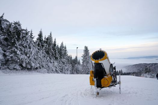 Yellow artificial snow cannon on Wasserkuppe ski resort in Rhoen Hesse Germany, on snowy mountain after fresh snow fall in 2022 december. High quality photo