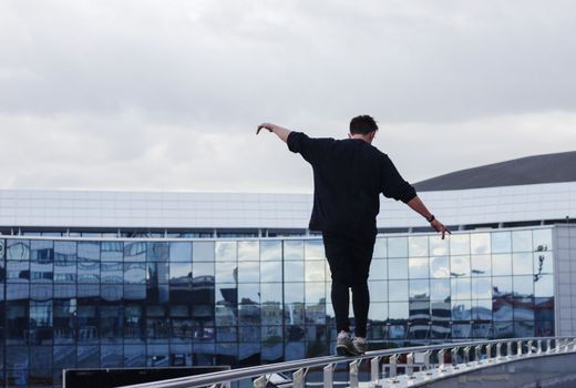 The guy walks along the railing at a height.