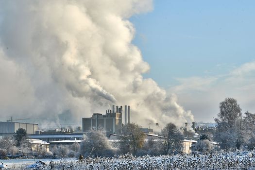 Environmental problem of pollution of environment and air in cities. Smoking industrial zone factory chimneys. View of large plant with Smoking pipes Smoke from the paper industry, which is running every day of the year. Photo taken December 2022 Air pollution in the city. Smoke from the chimney on blue sky background. High quality photo