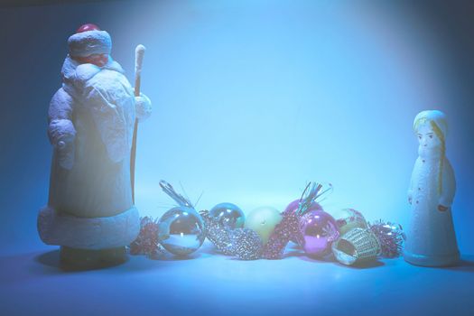 the calendar year just begun or about to begin. Xmas Santa Claus with granddaughter and New Year's toys on blue. Space for text. High quality photo