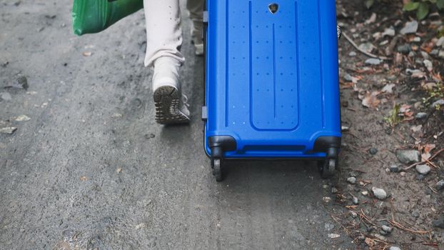 A guy with a suitcase walks through the forest floor