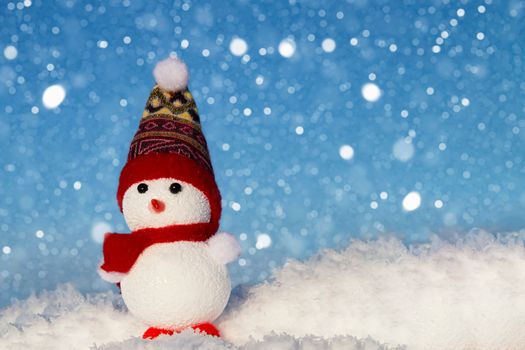 The snowman is standing in the snow and it is snowing. Festive Christmas card. Winter background for the design.