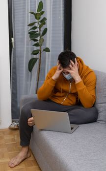 upset young man at home watching at laptop. High quality photo
