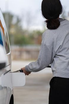 Rear view of woman in sport clothes refuelling the car.