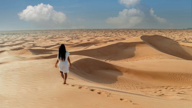 Dubai dessert sand dunes, Asian women on Dubai desert safari,United Arab Emirates, woman vacation in Dubai visit the sand dunes