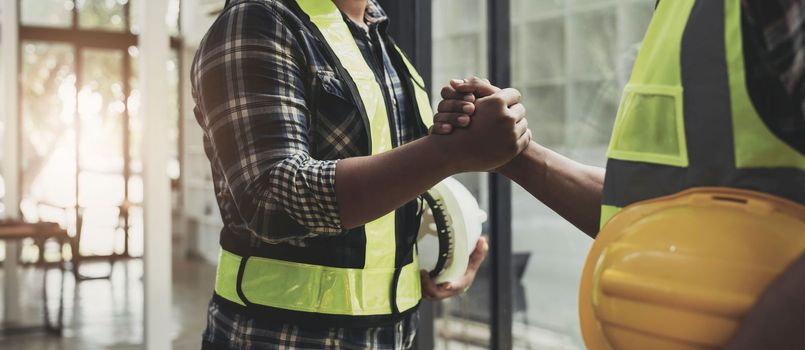 construction worker team hands shaking after consultation meeting to greeting start up plan new project contract in office center at construction site, teamwork, partnership and contractor concept..